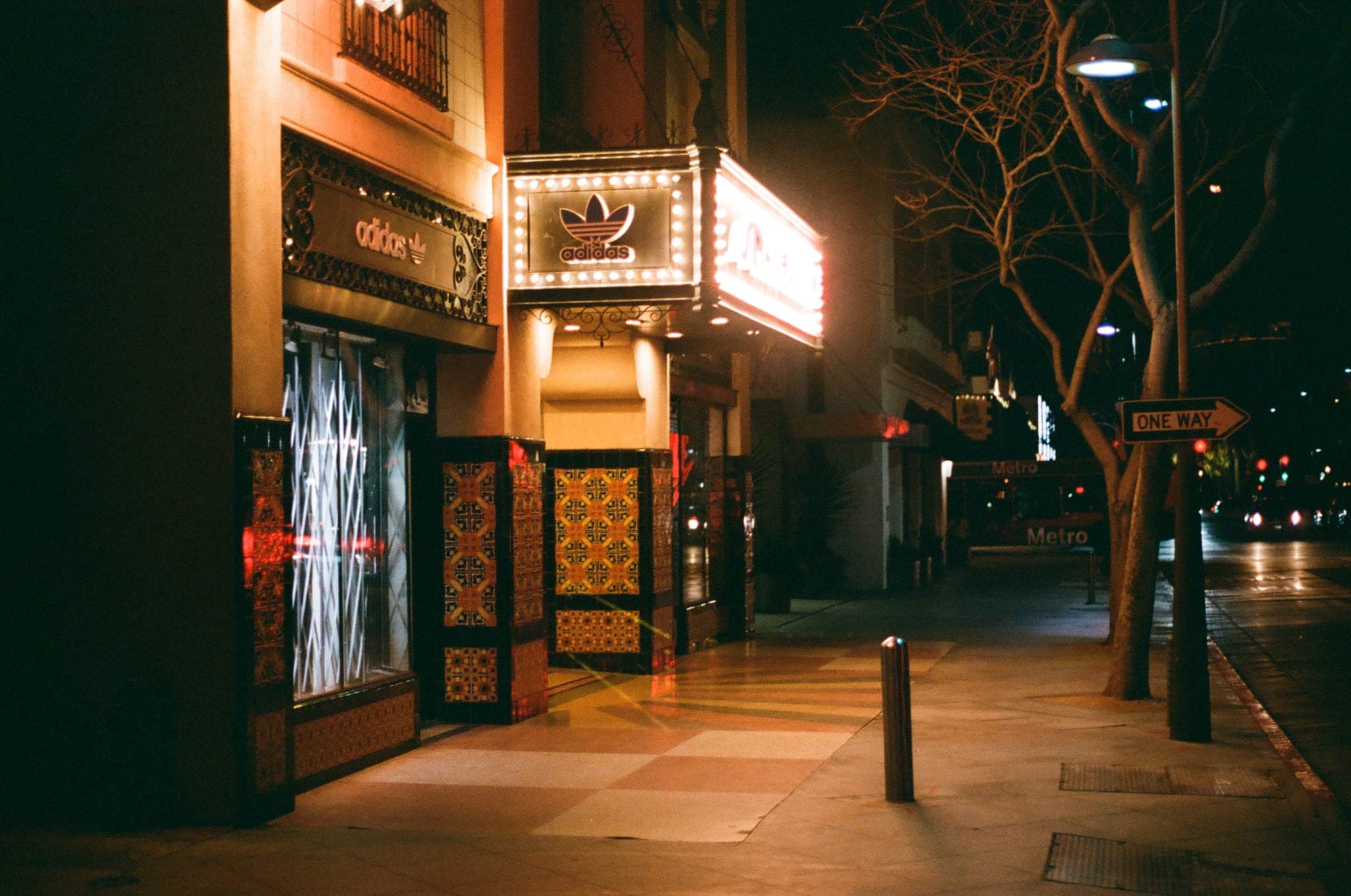 Neon-lit storefront on an empty city street at night, shot on film