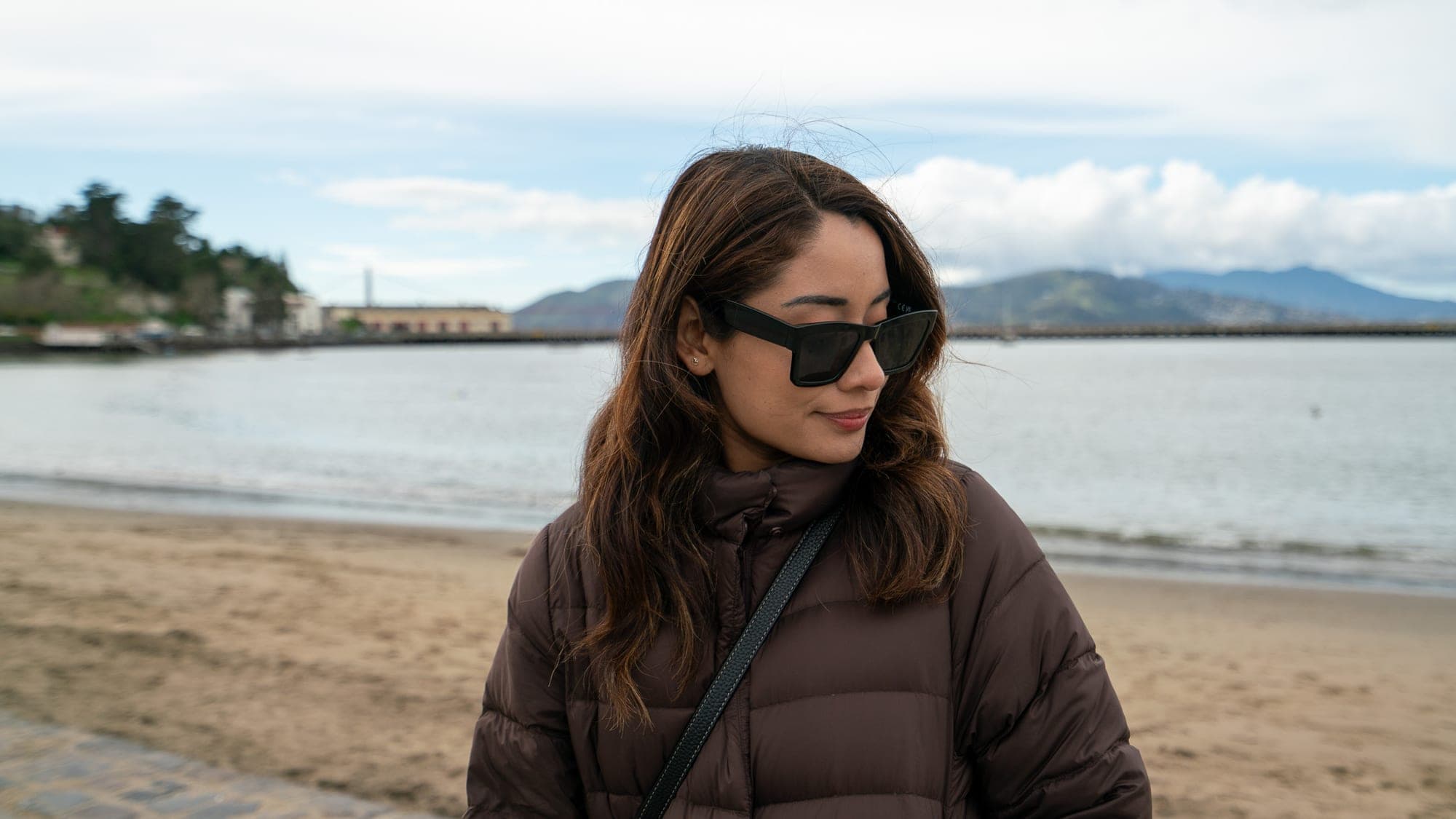 Smiling woman in sunglasses on a beach along the San Francisco bay