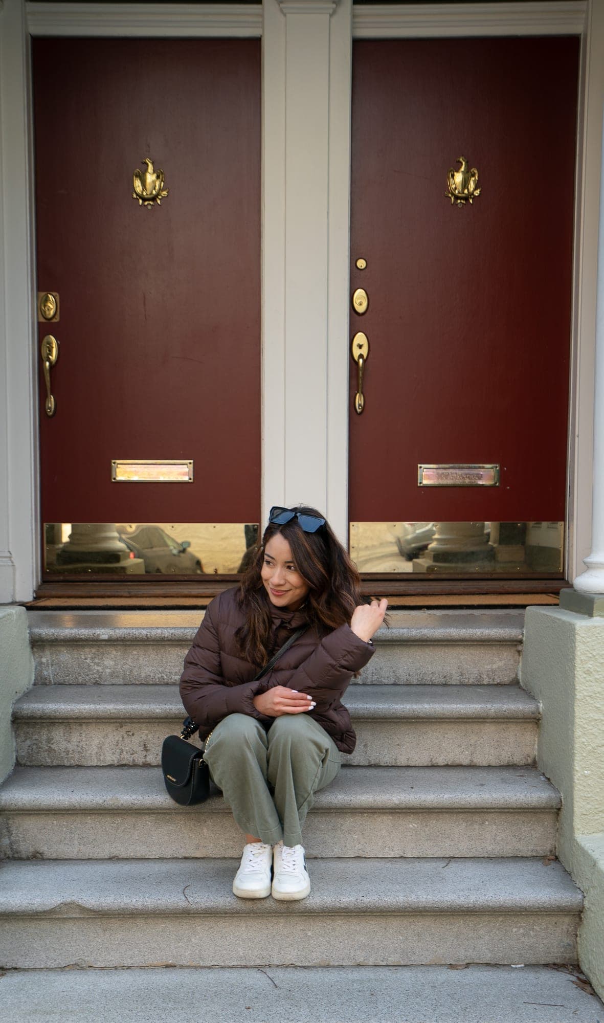 Candid portrait on a San Francisco doorstep framed by two red doors with brass details