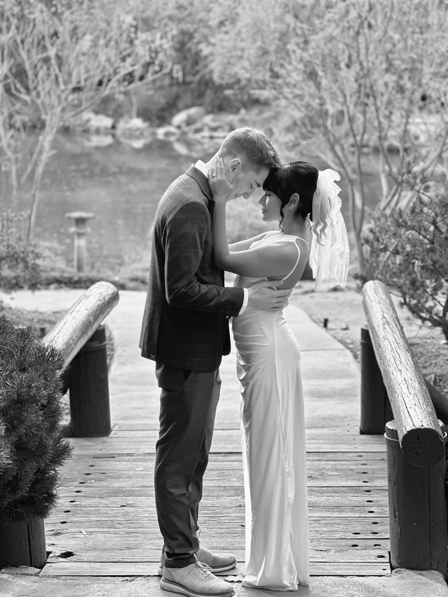 Black-and-white photo of a groom resting his forehead against his bride's