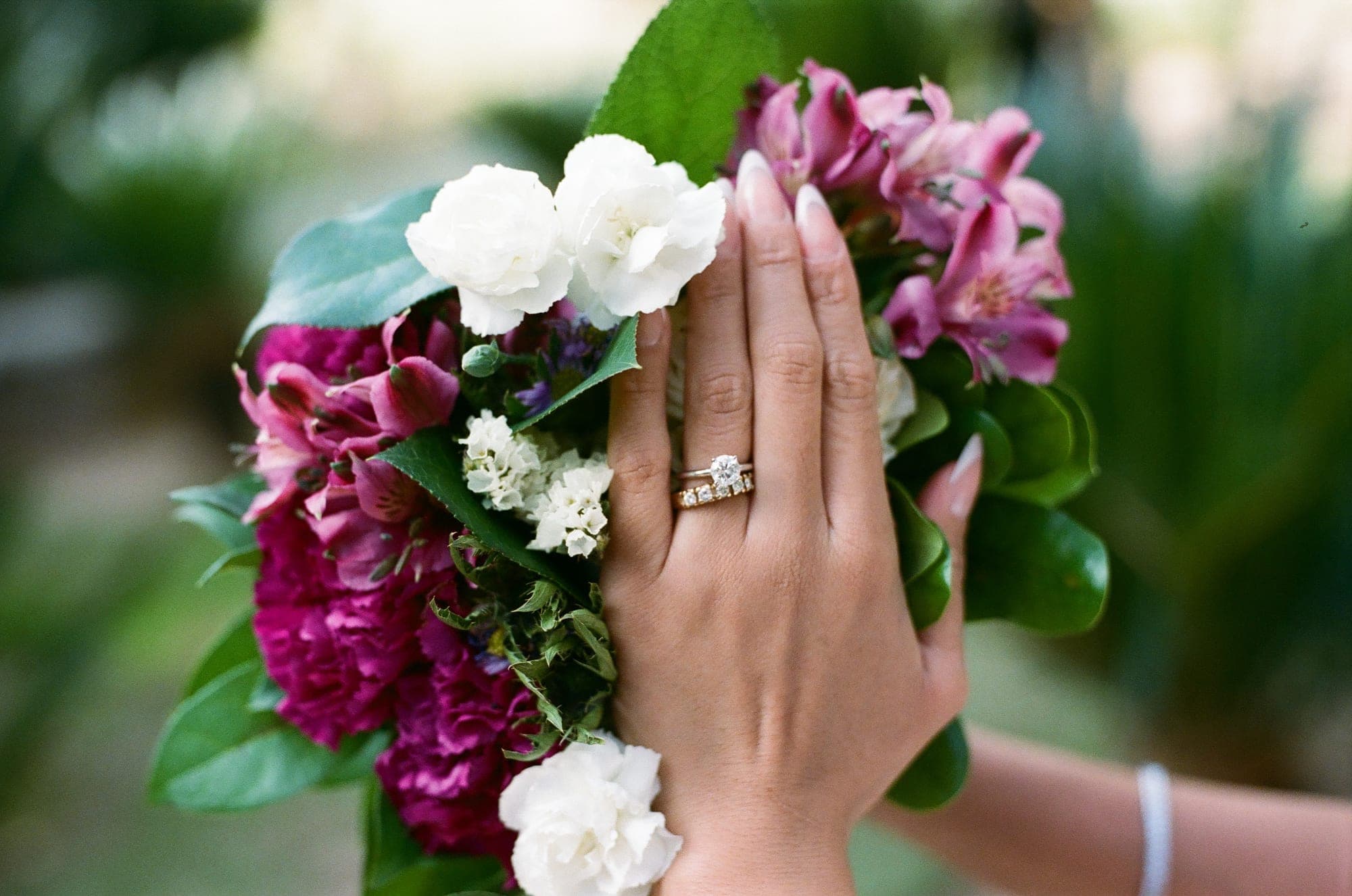 Bride's hand with wedding rings resting on a bouquet, shot on 35mm film