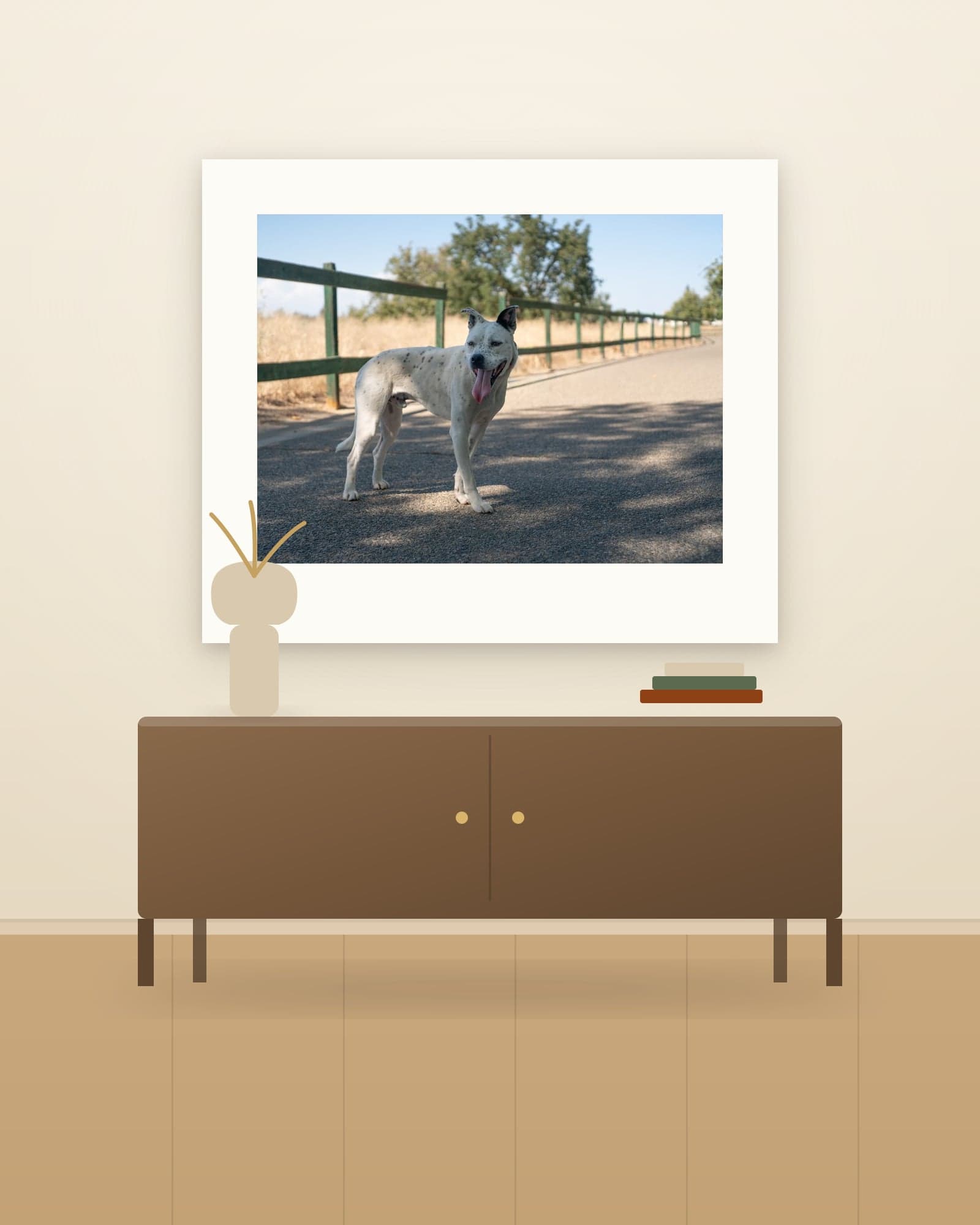 Fine art print of a spotted white dog, hung above a walnut credenza with a vase of dried grass in a modern living room